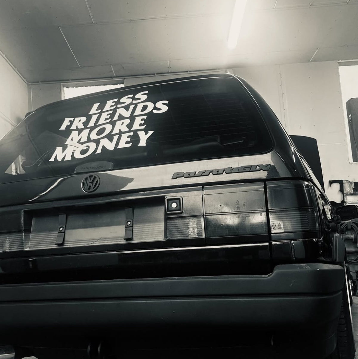 Less Friends More Money banner installed on car rear window