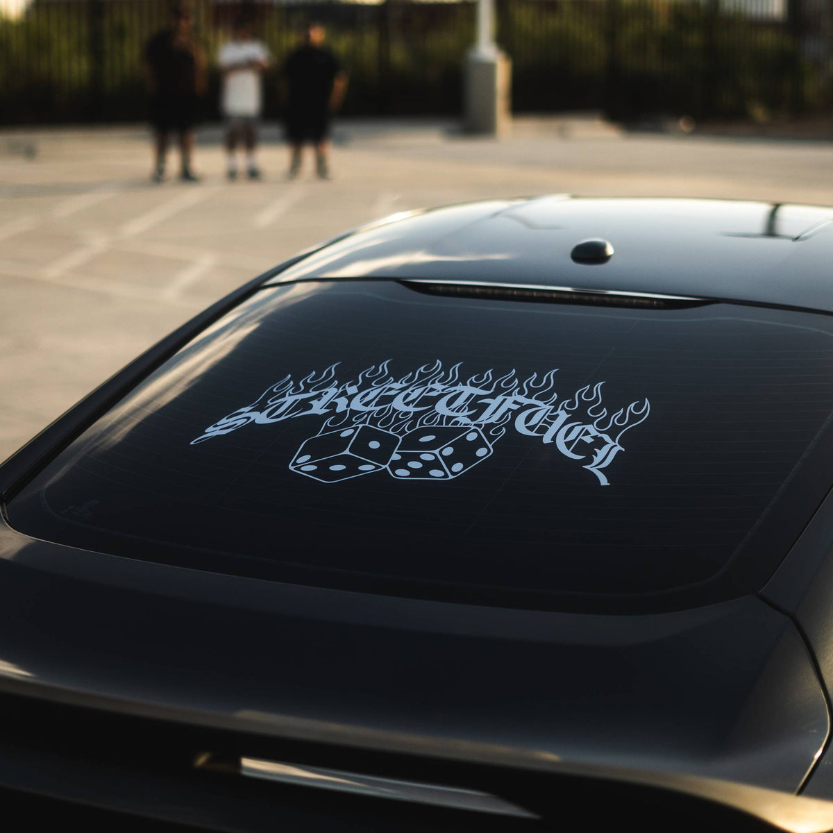 Rear windshield with no luck sticker, dice on flames.